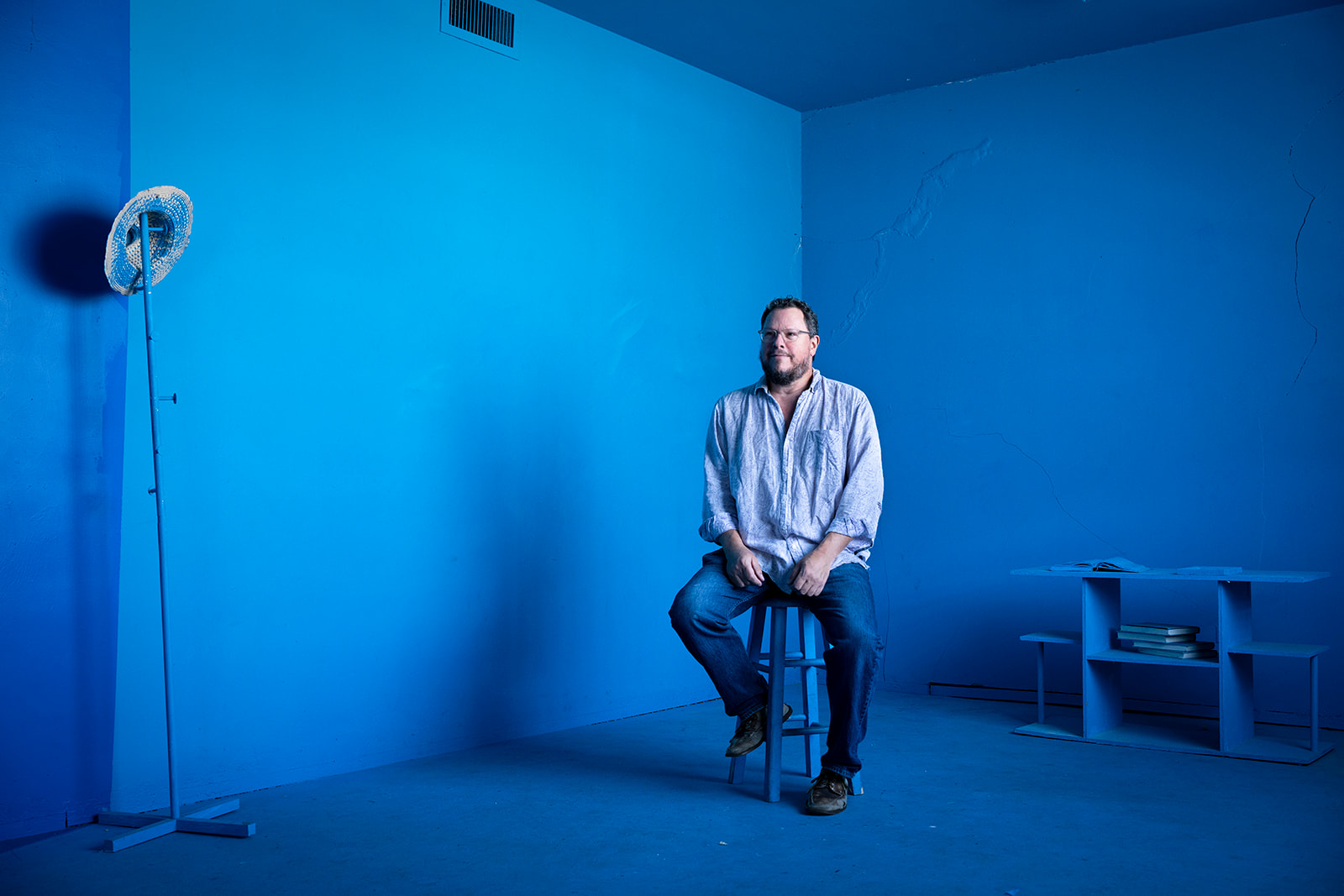 Tim Walter sits on a chair in an entirely blue room